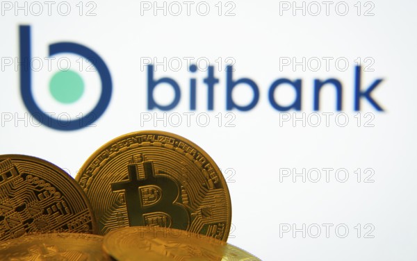 Dhaka, Bangladesh- 02 June 2025: Close-up of Bitcoin coins with the bitbank logo visible on a screen in the background