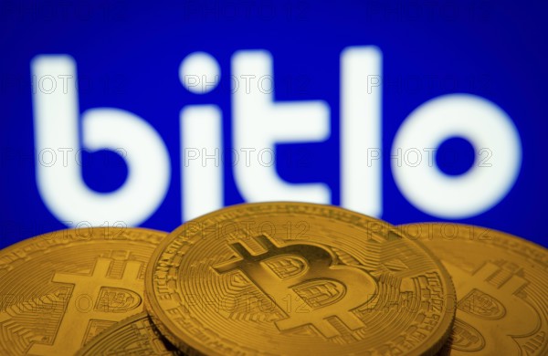 Dhaka, Bangladesh- 03 Sep 2025: Close-up of Bitcoin coins with the Bitlo logo visible on a screen in the background