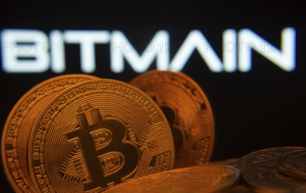 Dhaka, Bangladesh- 15 June 2025: Close-up of Bitcoin coins with the Bitmain logo visible on a screen in the background