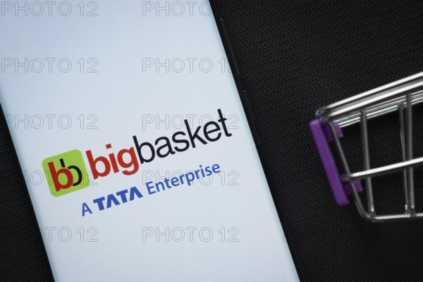 Dhaka, Bangladesh- 03 July 2025: A smartphone displaying the BigBasket logo next to a miniature shopping cart on a background
