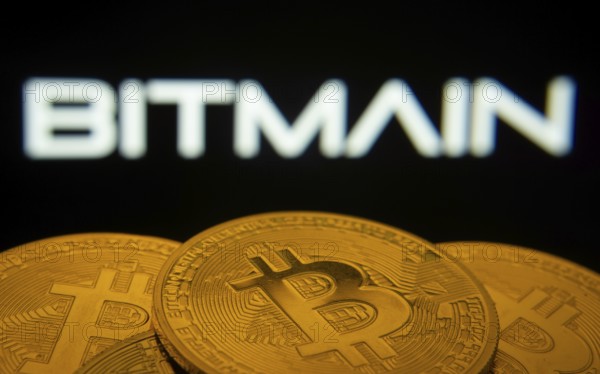 Dhaka, Bangladesh- 03 Sep 2025: Close-up of Bitcoin coins with the Bitmain logo visible on a screen in the background