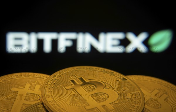 Dhaka, Bangladesh- 15 June 2025: Close-up of Bitcoin coins with the Bitfinex logo visible on a screen in the background