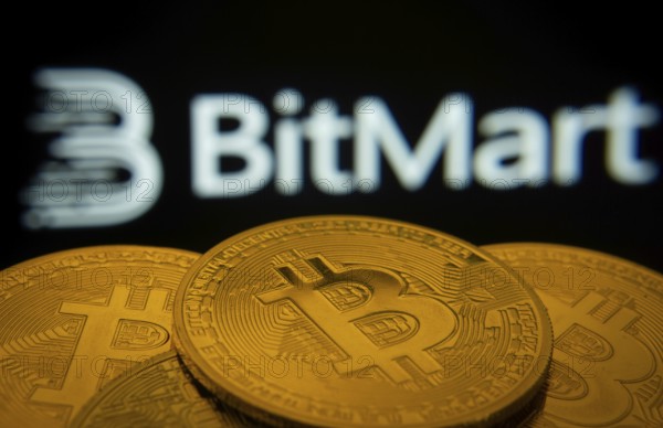 Dhaka, Bangladesh- 03 Sep 2025: Close-up of Bitcoin coins with the Bitmart logo visible on a screen in the background