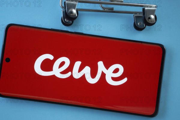 Dhaka, Bangladesh- 03 July 2025: Smartphone screen showing the Cewe logo with shopping cart wheels on a blue background