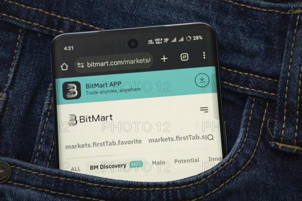 Dhaka, Bangladesh- 15 June 2025: A smartphone displaying the BitMart.com web interface peeks out of a denim pocket