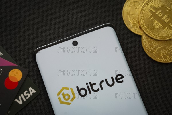 Dhaka, Bangladesh- 06 Sep 2025: Smartphone displaying Bitrue logo surrounded by Bitcoin coins and payment cards