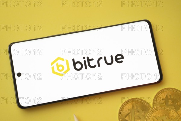 Dhaka, Bangladesh- 26 Aug 2025: Bitrue logo on smartphone screen near Bitcoin coin and QR code on background