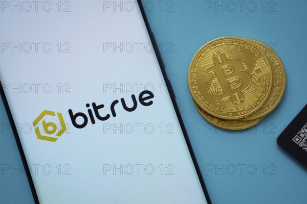 Dhaka, Bangladesh- 03 Sep 2025: Bitrue logo on smartphone screen near Bitcoin coin and QR code on blue background