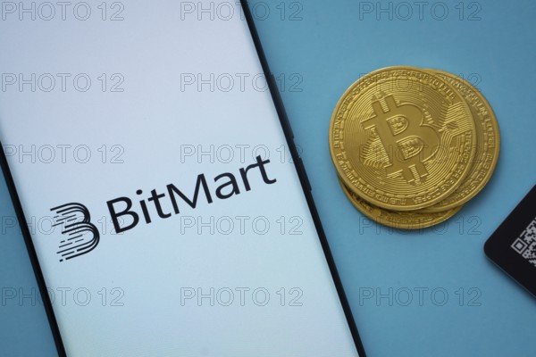 Dhaka, Bangladesh- 03 Sep 2025: Bitmart logo on smartphone screen near Bitcoin coin and QR code on blue background