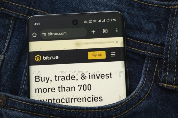 Dhaka, Bangladesh- 15 June 2025: A smartphone displaying the Bitrue.com web interface peeks out of a denim pocket