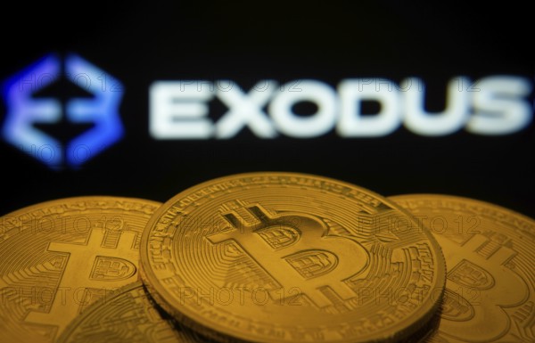 Dhaka, Bangladesh- 06 Sep 2025: Close-up of Bitcoin coins with the Exodus logo visible on a screen in the background