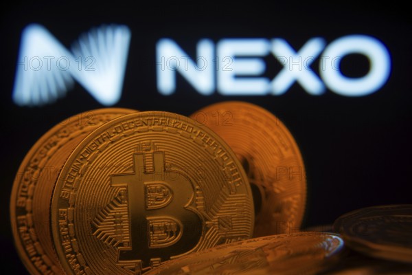 Dhaka, Bangladesh- 06 Sep 2025: Close-up of Bitcoin coins with the Nexo logo visible on a screen in the background