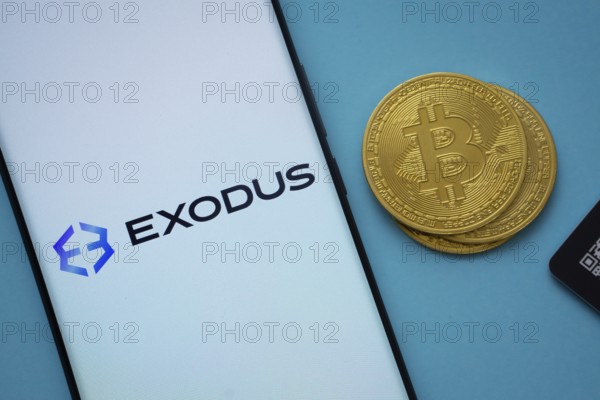 Dhaka, Bangladesh- 06 Sep 2025: Exodus logo on smartphone screen near Bitcoin coin and QR code on blue background