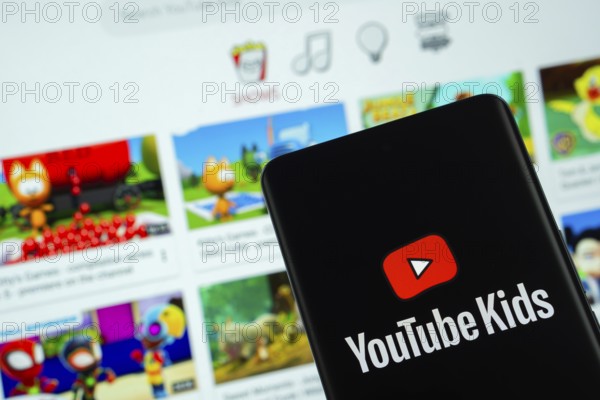 Dhaka, Bangladesh - 06 Sep 2025: The logo of Youtube Kids is displayed on a smartphone screen, and the website is visible on a computer screen in the background