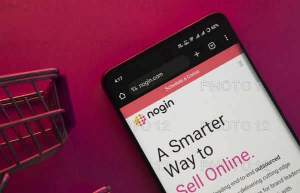Dhaka, Bangladesh- 23 June 2025: A smartphone displaying the nogin website with a shopping cart is shown on a vibrant background