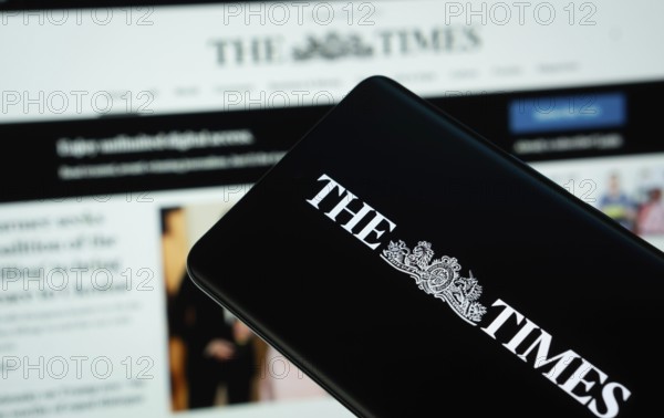 Dhaka, Bangladesh - 18 March 2025: The logo of the times is displayed on a smartphone screen, and the website is visible on a computer screen in the background