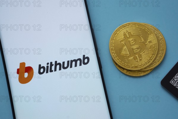 Dhaka, Bangladesh- 07 May 2025: Bithumb logo on smartphone screen near Bitcoin coin and QR code on blue background