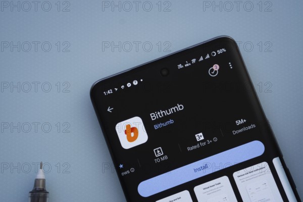 Dhaka, Bangladesh- 07 May 2025: On a blue surface, a smartphone displays the Bithumb app within the Google Play Store