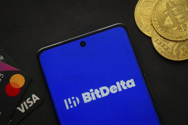 Dhaka, Bangladesh- 02 June 2025: Smartphone displaying BitDelta logo surrounded by Bitcoin coins and payment cards