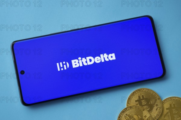 Dhaka, Bangladesh- 02 June 2025: BitDelta logo on smartphone screen near Bitcoin coin and QR code on blue background