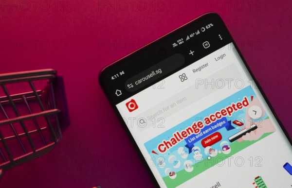 Dhaka, Bangladesh- 23 June 2025: A smartphone displaying the Carousell website with a shopping cart is shown on a vibrant background