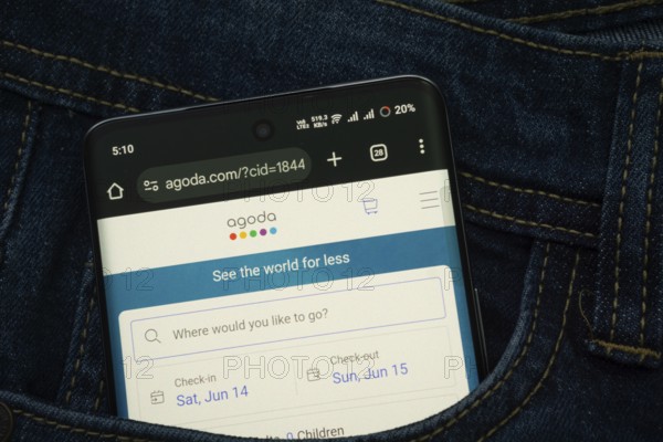 Dhaka, Bangladesh- 15 June 2025: A smartphone displaying the Agoda.com web interface peeks out of a denim pocket