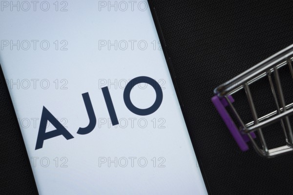 Dhaka, Bangladesh- 03 July 2025: A smartphone displaying the AJIO logo next to a miniature shopping cart on a background