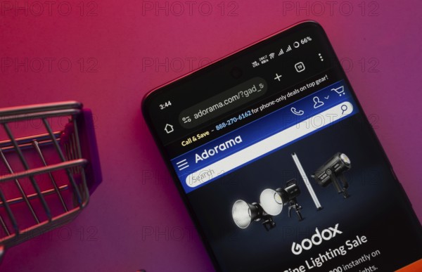Dhaka, Bangladesh- 23 June 2025: A smartphone displaying the Adorama website with a shopping cart is shown on a vibrant background