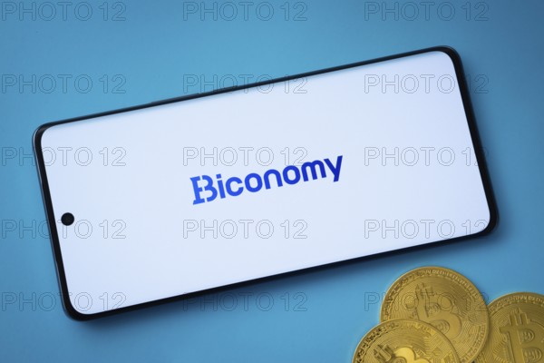 Dhaka, Bangladesh- 02 June 2025: Biconomy logo on smartphone screen near Bitcoin coin and QR code on blue background