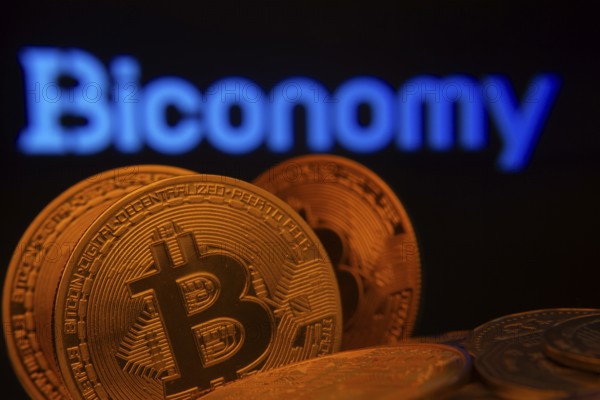 Dhaka, Bangladesh- 03 Sep 2025: Close-up of Bitcoin coins with the Biconomy logo visible on a screen in the background