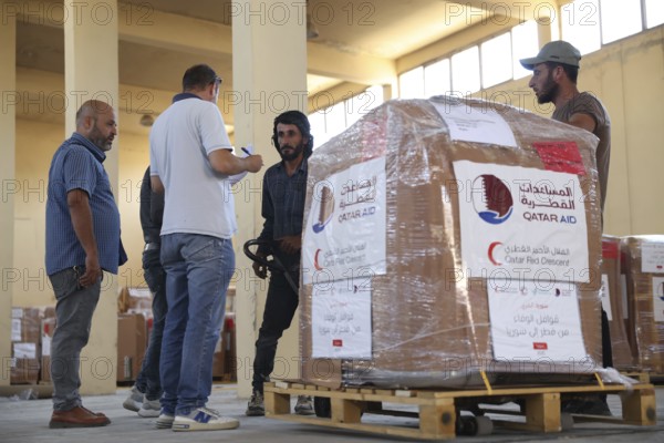 Relief workers unload boxes of medical aid provided by Qatar at Damascus International Airport, part of the humanitarian bridge supporting Syria's recovery and reconstruction after the fall of Bashar al-Assad, Damascus, Damascus, Syria