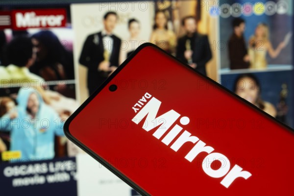 Dhaka, Bangladesh - 18 March 2025: The logo of Daily Mirror is displayed on a smartphone screen, and the website is visible on a computer screen in the background
