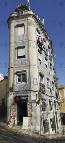 A tall, narrow building on a sloping street with typical facades, Lisbon, Portugal