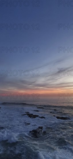 Sunset over a peaceful ocean with rocks in the foreground, hiking the Fisherman's trail, Rota Vicentina, Porto Covo, Alentejo region, Portugal