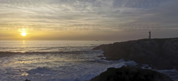A lighthouse stands on cliffs in front of a sunset over the sea, hiking the Fisherman's Trail, Rota Vicentina, Porto Covo, Alentejo region, Portugal