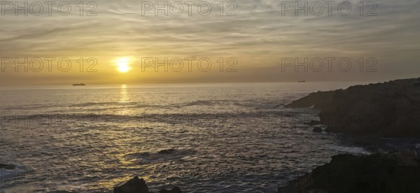 Calm sunset over the sea with two ships on the horizon, hiking the Fisherman's trail, Rota Vicentina, Porto Covo, Alentejo region, Portugal