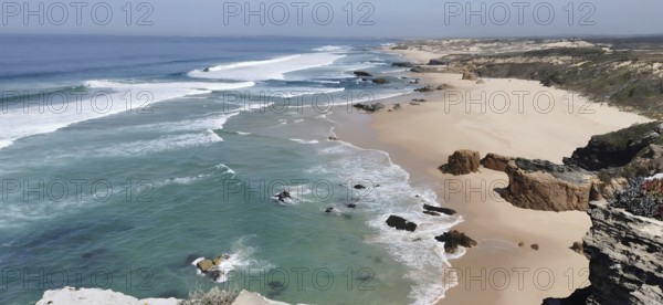 Wide view of sandy beach with waves of sea and cliffs, hiking on the Fisherman's Trail, fishing trail, Rota Vicentina, Portugal