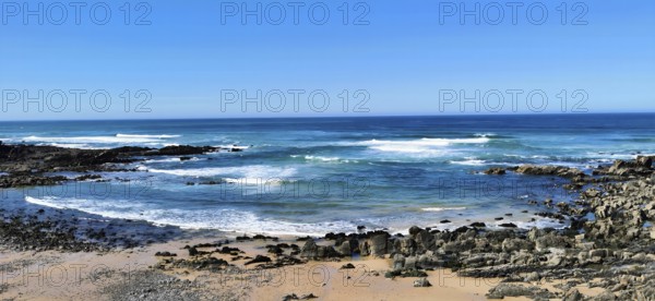 Hiking the fishing trail, Rota Vicentina, Clear blue sky with waves in blue water hitting rocky coast, Portugal