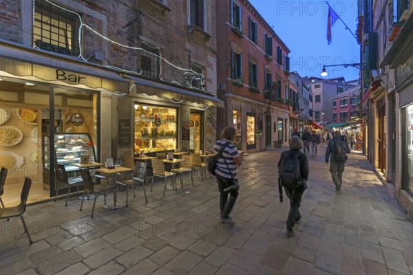 Photographers traveling in the old town of Venice, Veneto, Italy in the evening
