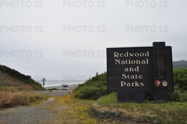 A sign at the entrance to Redwood National and State Park near a coastline, Redwood National Park, California, USA