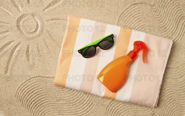 Drawing on the sand, sun and waves, sunglasses, with an orange bottle, beach towel, sun spray, on the sand, top view, no people