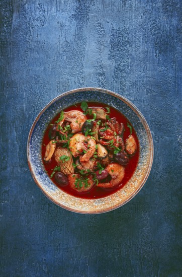 Seafood in tomato sauce with olives, on a dark blue background