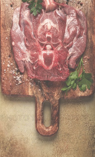 Raw steak, veal neck on the bone, fresh meat, on a cutting board, with spices, top view, without people
