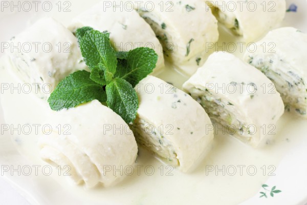 Gebjalia, a traditional Megrelian dish, cold appetizer of cheese with mint, Georgian cuisine, on a white plate, homemade