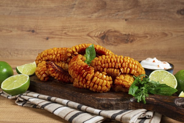 Corn ribs, with cream sauce, spices and lime, appetizer, on a wooden cutting board, homemade, no people