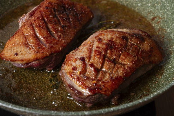Cooking duck breast, in a frying pan, fried, with spices and herbs, close-up, no people