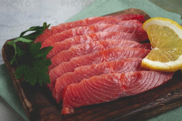 Chum salmon, cold smoked, sliced, on a cutting board, with lemon and parsley, top view, close-up, no people