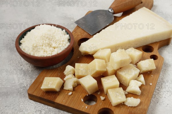 Freshly sliced and grated cheese, parmesan cheese, Gran gusto. Grana padano. on a wooden chopping board, rustic style, no people