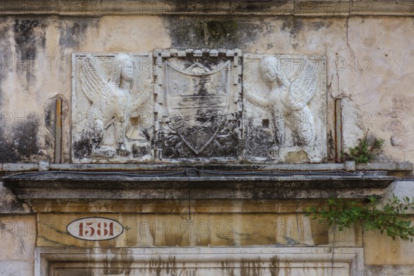 Relief of a coat of arms framed by two sphinxes on a historic palazzo, Venice, Veneto, Italy