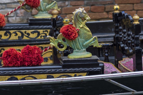 Mythological horse figures and red pompoms decorate the gondola, Venice, Veneto, Italy